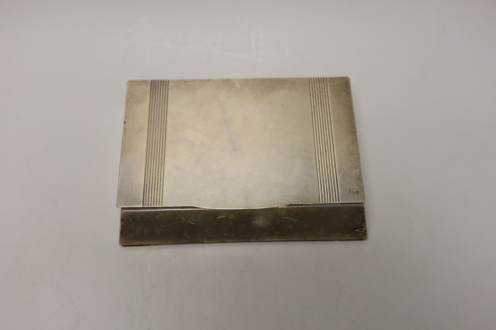 A George VI engine turned silver mounted cigarette box, of tapering rectangular form, the lid interior with engraved inscription relating to the Royal Hong Kong Golf Club, London, 1947, 17.7cm.
